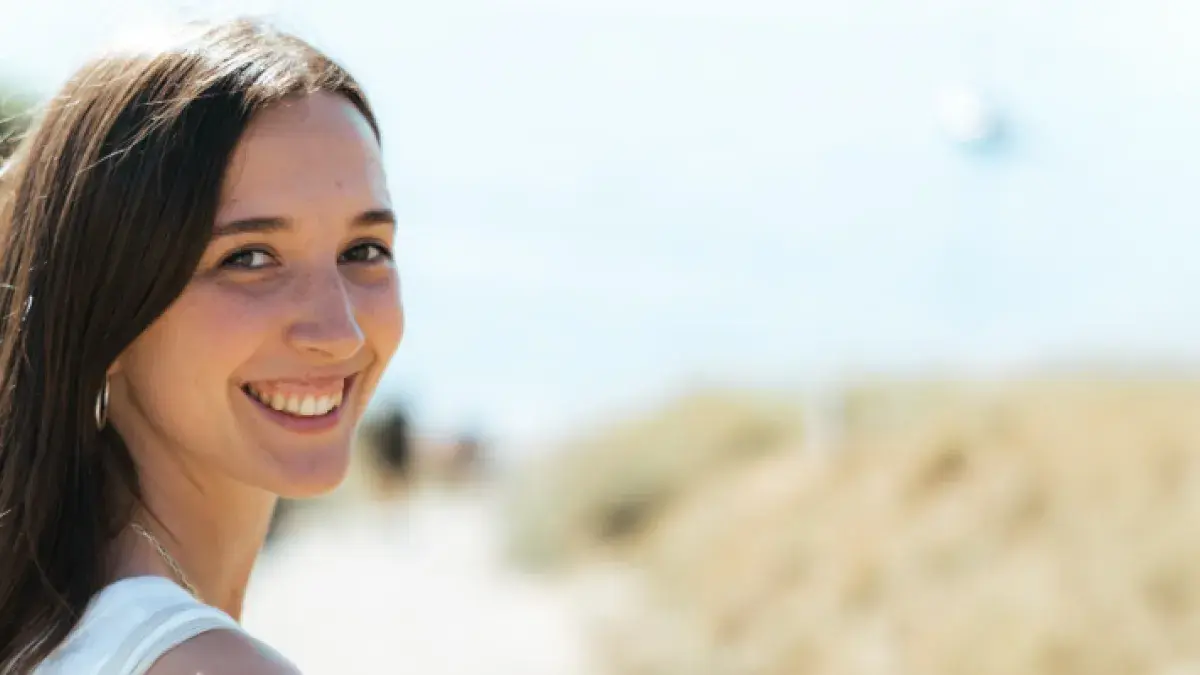 Colour head and shoulders photo of Sophie stood looking back at the camera and smiling