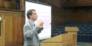 Colour photo of Professor Jeremy Carrette speaking at a lectern in the Assembly Hall