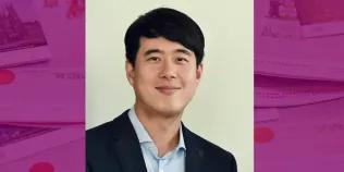 Colour head and shoulders photo of Jaekook Lee smiling at the camera