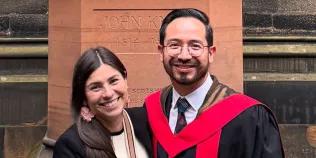 Colour head and shoulders photo of Israel Guerrero smiling at the camera with another person