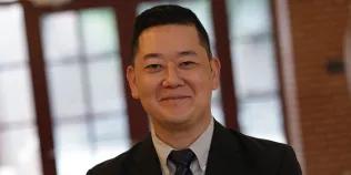 Colour head and shoulders photo of Matthew Kim smiling at the camera