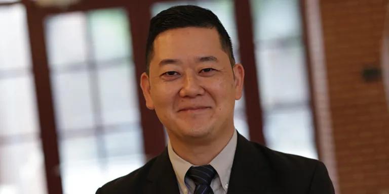 Colour head and shoulders photo of Matthew Kim smiling at the camera