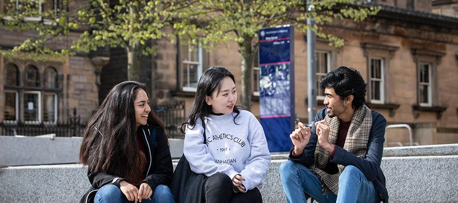 Colour photo of University of Edinburgh students sat talking together in Bristo Square