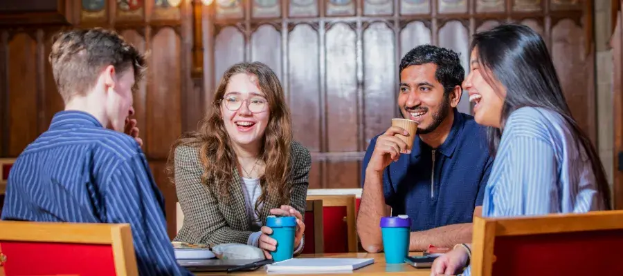Colour photo of students sat smiling together in the Rainy Hall