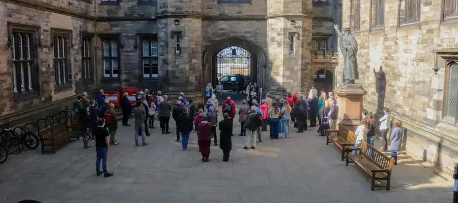 Colour photo of students, staff and the general public gathered in the Quad listening to Professor Helen Bond speak.