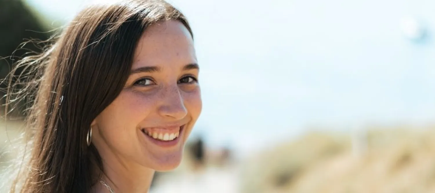 Colour head and shoulders photo of Sophie smiling as she looks back at the camera