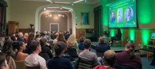 Colour photo of people sat in the Martin Hall watching as Jeremy Carrette and Shannon Vallor talk whilst sat on seats on the stage in the hall