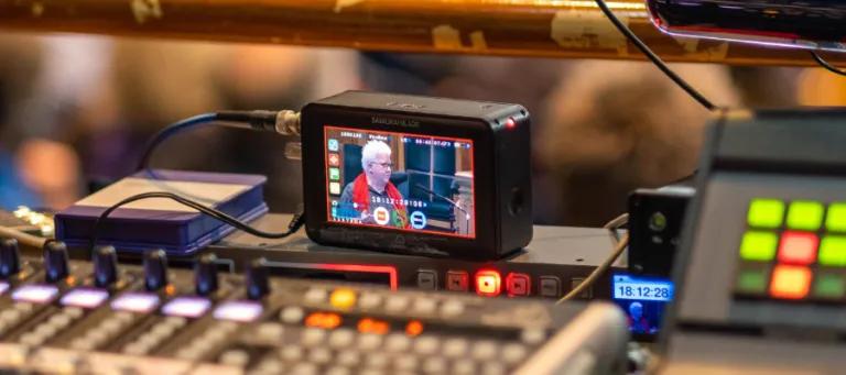 Colour photo of a viewfinder on a desk displaying a person talking