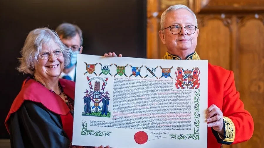 Colour Image of the Lord Lyon presenting Professor Susan Hardman Moore with the New College coat of Arms