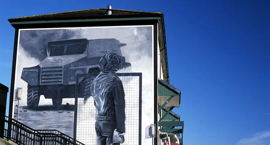 The Rioter mural - a gray painting on a building showing a rioter with a wire mesh shield facing an armoured car