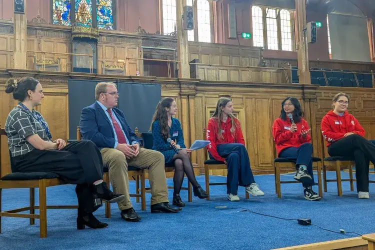 Staff and current students from the School of Divinity in discussion sitting in chairs in a row