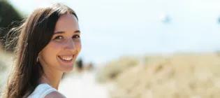 Colour head and shoulders photo of Sophie stood looking back at the camera and smiling