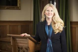 Colour head and shoulders photo of Professor Helen Bond stood smiling at the camera in Martin Hall