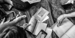 Black and white photo of community members handling notebook replicas