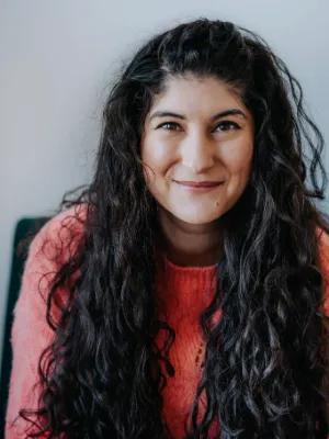 Colour photo of Nadine Aisha Jassat smiling at the camera