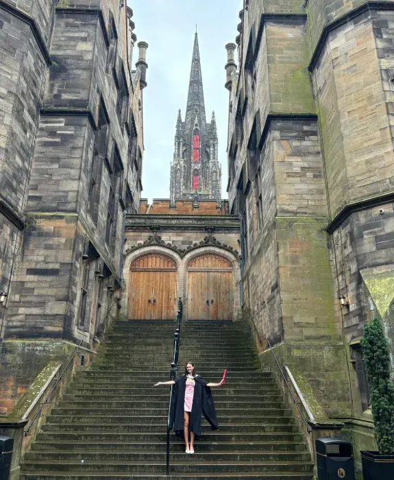 Colour photo of Eliza Light stood smiling at the camera in the New College Quad