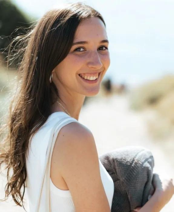 Colour head and shoulders photo of Sophie smiling as she looks back at the camera